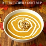 a bowl of butternut squash carrot soup ready to serve in a white bowl on a wooden table with fall accents