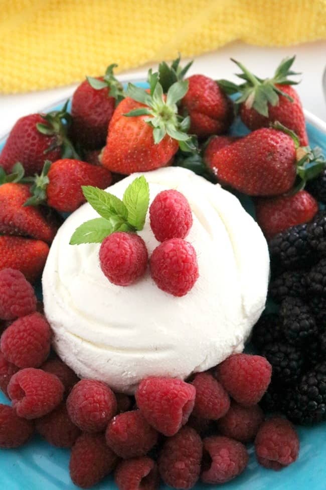Whole milk ricotta cheese formed into a ball surrounded by fresh berries; strawberries, raspberries, and blackberries.