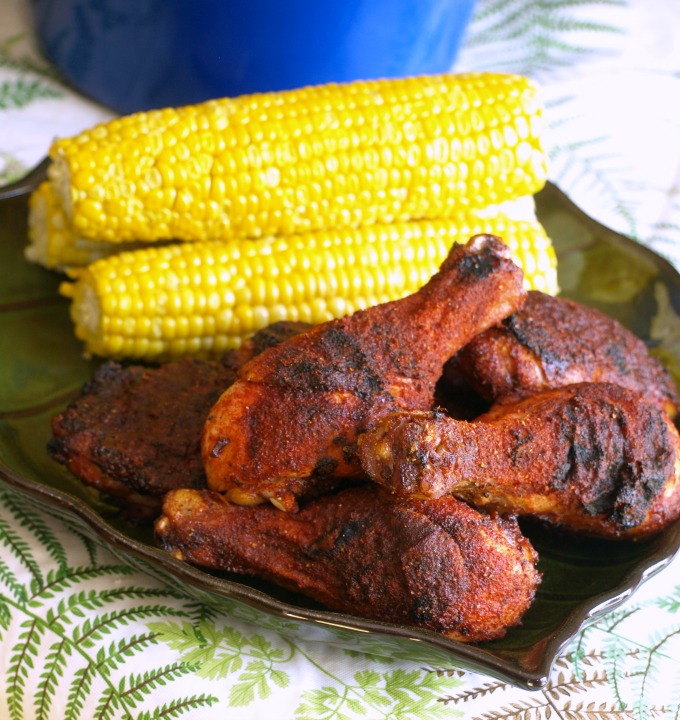 a plate of Memphis-style dry-rubbed chicken with ears of yellow corn.