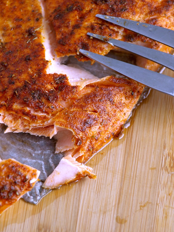 A piece of Cajun salmon that has been cut into to show how tender and juicy the flesh is. 