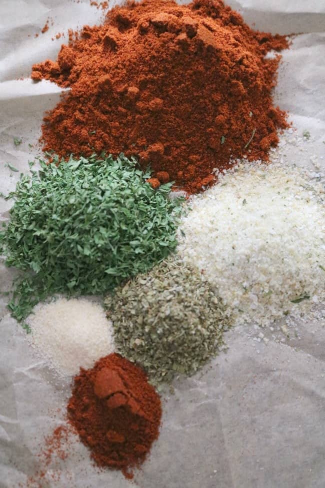 an image of herbs and spices on a sheet of parchment ready to be added to the ground pork for making homemade linguica sausage