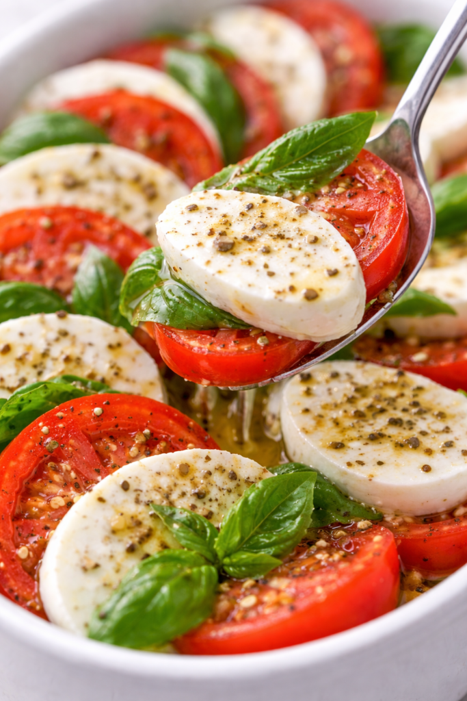 Classic Caprese Salad Recipe with Fresh Mozzarella and Basil 6 Caprese salad recipe close-up with a spoon lifting tomato, mozzarella, and basil with a glossy olive oil finish.