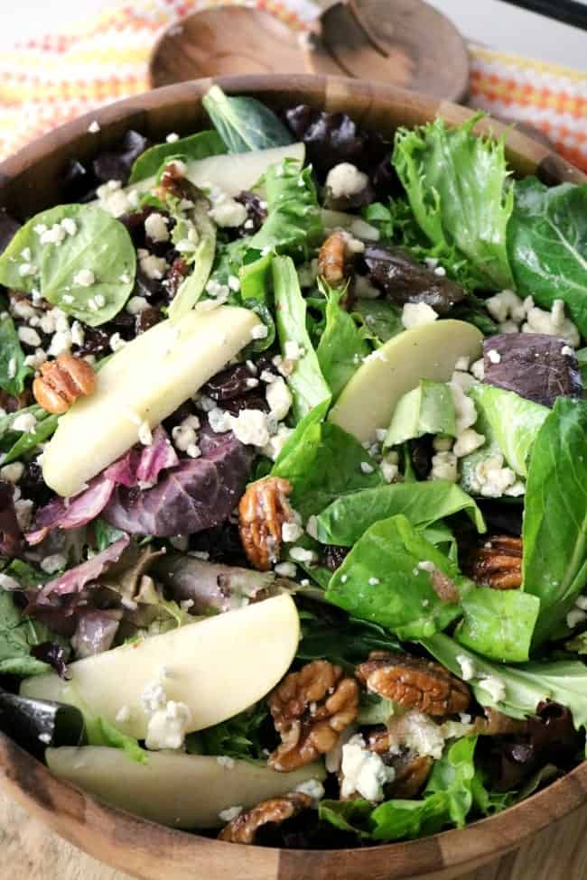 An overhead shot of Apple Pecan Blue Cheese Salad with Apple Vinaigrette in a wooden bowl after being tossed.