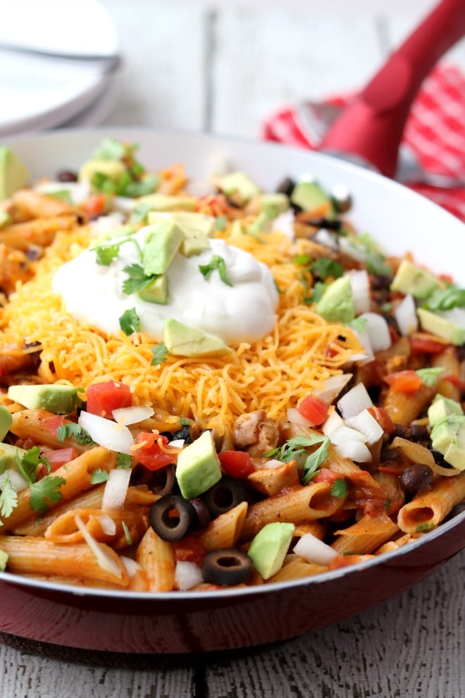 Cropped View of a Red Skillet with Cooked Chicken, Pasta, Black Beans and Salsa topped with Sour Cream