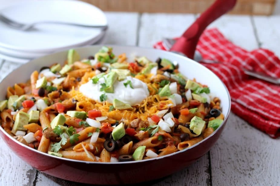 Red Skillet Containing Cooked Chicken, Pasta, Black Beans and Salsa topped with Sour Cream