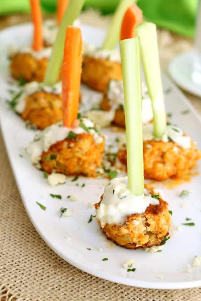 A tray of buffalo chicken meatballs with carrot stick skewers for a portable party snack.