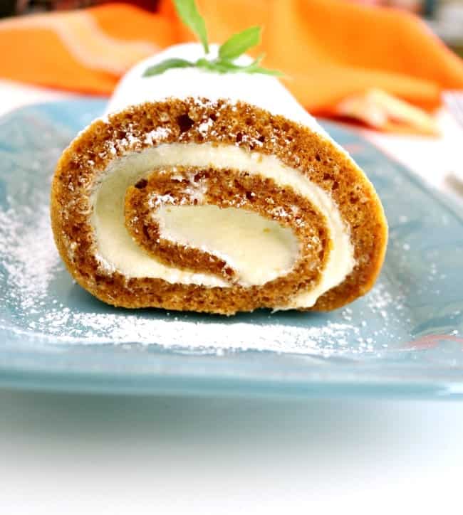 A shot of an end of a pumpkin cake roll showling the swirl of cake and cream.