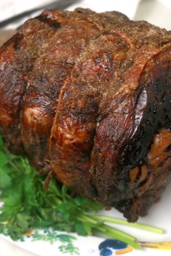 A whole slow-roasted prime rib on a platter ready to be carved for serving.
