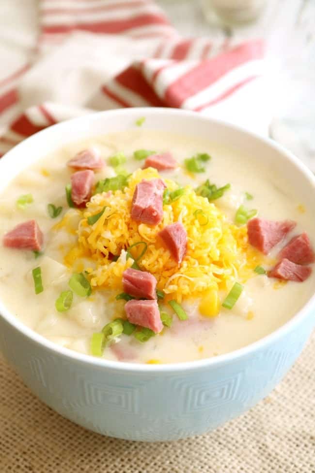 Ham Chowder in a bowl topped with shredded cheddar cheese and chives. 