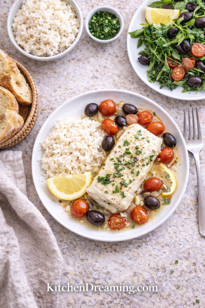 Mediterranean Poached Cod - A High Protein Low Calorie Dinner 4 Mediterranean Poached Cod served with rice, olives, tomatoes, and lemon.