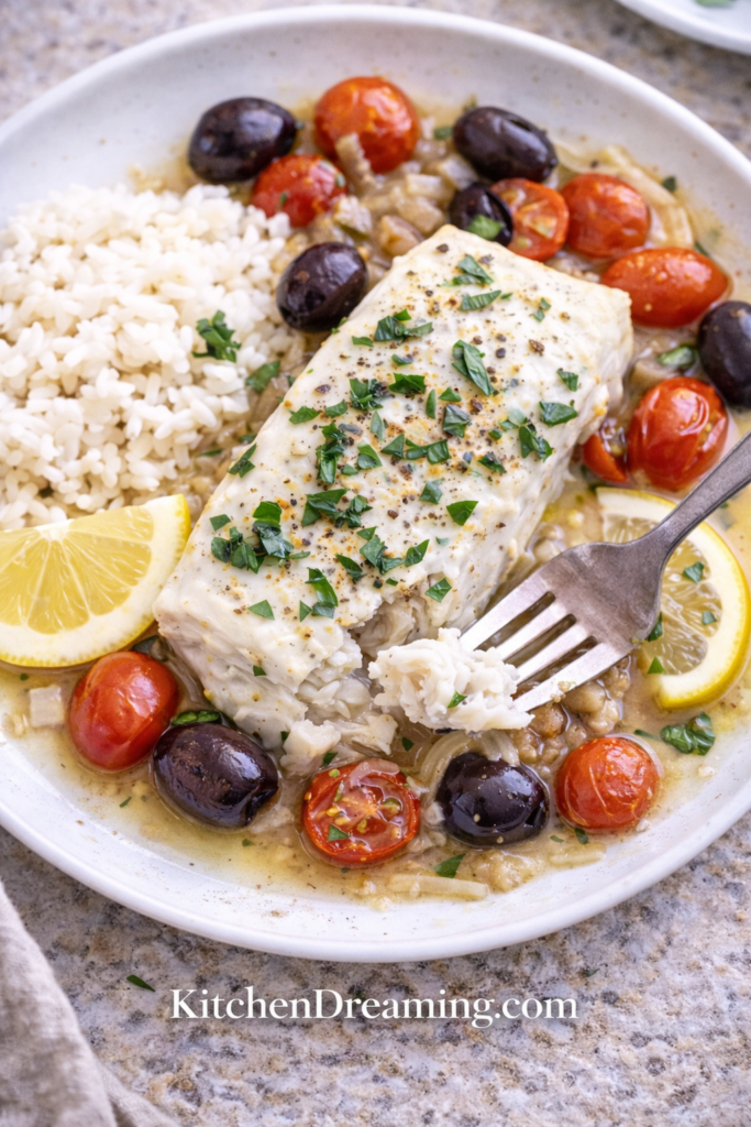 Mediterranean Poached Cod - A High Protein Low Calorie Dinner 6 Fork lifting flaky Mediterranean Poached Cod with tomatoes and olives.