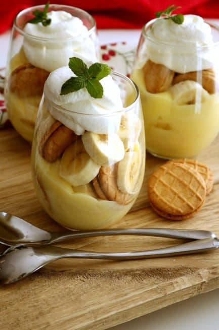 glasses of peanut butter banana pudding topped with freshly whipped cream and mint