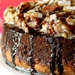 A close-up photo of the side and coconut-pecan topping of a German Chocolate cheesecake.