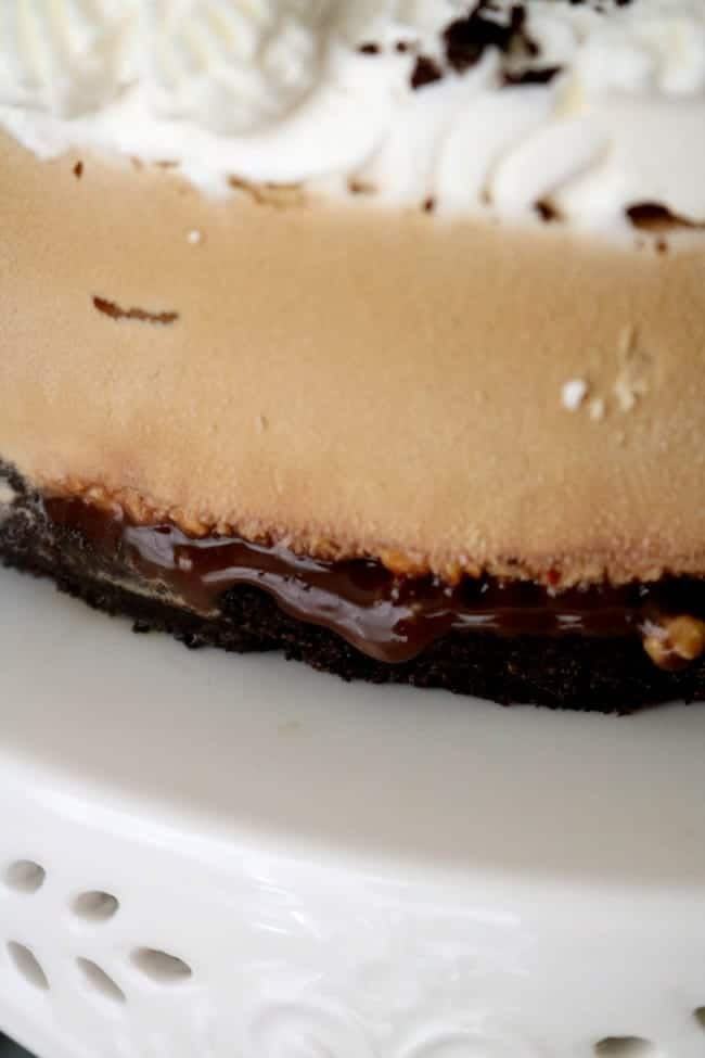 close up image of the side of the frozen mudslide pie. Homemade fudge oozes from between the layers.