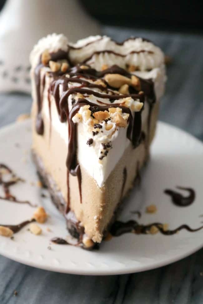 an image of a slice of mudslide pie looking down the point. The slice is drizzled with extra fudge sauce and sprinkled with chopped peanuts