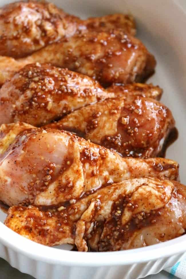 Chicken drumsticks coated in garlic-paprika marinade placed in a casserole pan in alternating directions.