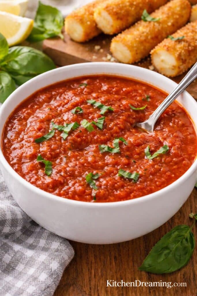 Carrabba’s Marinara Sauce Recipe in a white bowl with basil, served as a copycat restaurant marinara for dipping mozzarella sticks and pasta.