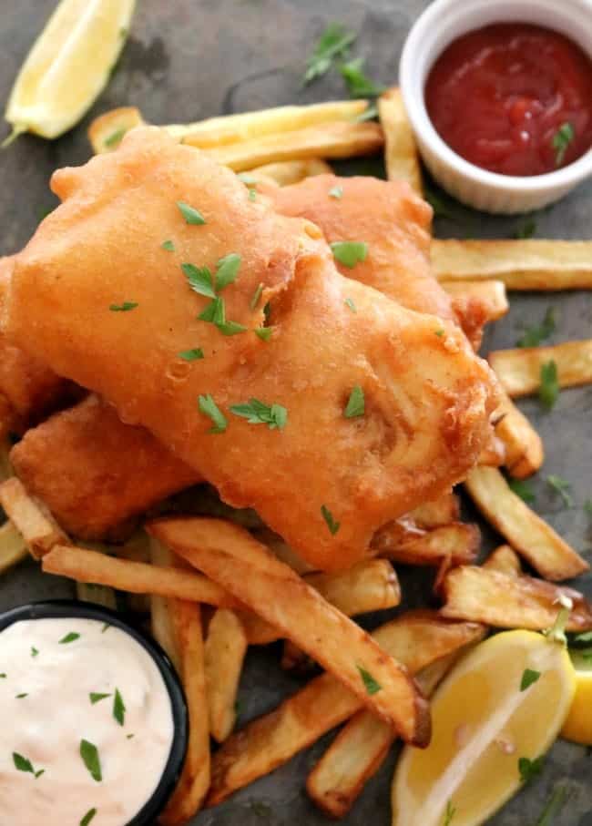 A plate of British Pub-style Fried Fish, Savory, golden brown, beer-battered cod fillets served with french fries, coleslaw, lemon wedges, and tangy tartar sauce. #British #PubFood #GlobalStreetFood #FriedFish #30MinuteMeals #KitchenDreaming