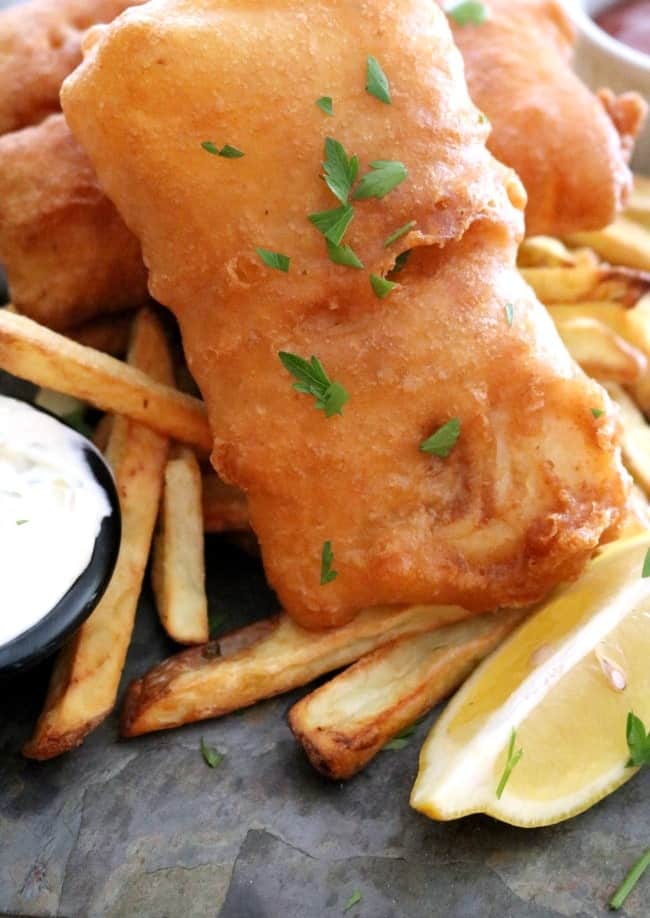 A plate of British Pub-style Fried Fish, Savory, golden brown, beer-battered cod fillets served with french fries, coleslaw, lemon wedges, and tangy tartar sauce. #British #PubFood #GlobalStreetFood #FriedFish #30MinuteMeals #KitchenDreaming