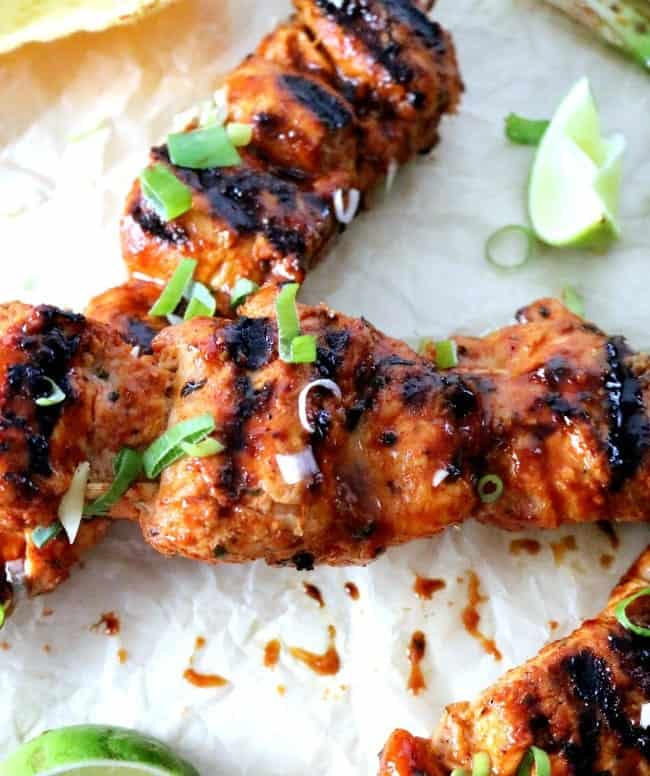 A close up photo of grilled spicy Korean chicken skewers