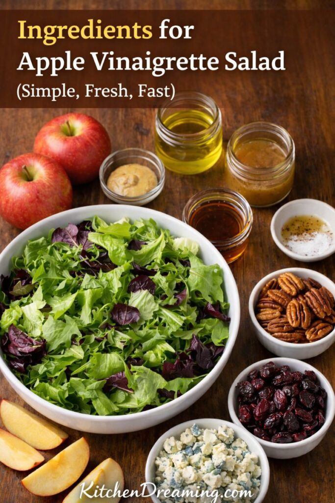 Ingredients for apple vinaigrette salad, including salad greens, apples, pecans, dried fruit, blue cheese, olive oil, and apple cider vinegar.