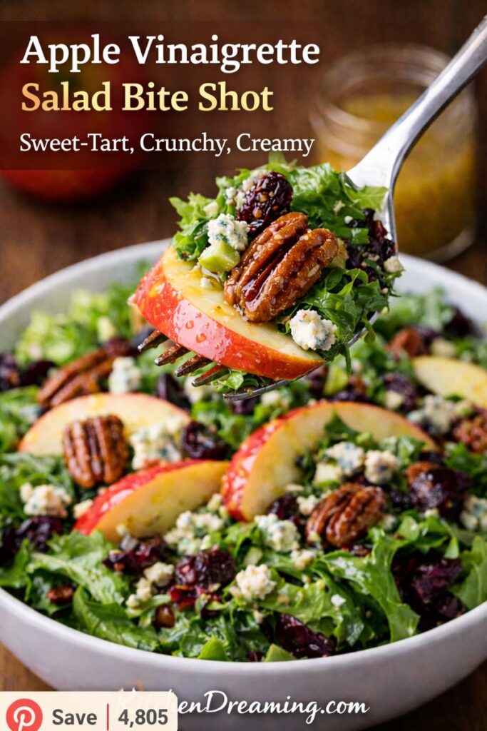 Forkful bite shot of apple vinaigrette salad with apple slices, pecans, dried fruit, and blue cheese coated in apple vinaigrette dressing.