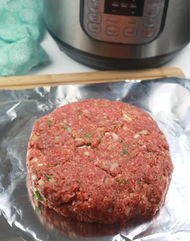 Meatloaf mixture shaped into a round loaf for the instant pot pressure cooker on aluminum foil to make a packet.