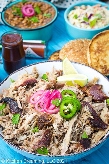Shredded pulled pork in a bowl  topped with pickled red onion and jalapenos.  