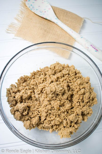 A clear mixing bowl containing the cinnamon streusel crumb topping mixture.