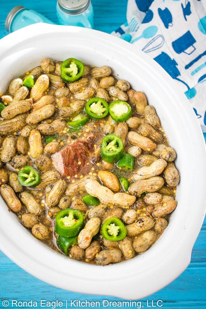 The ingredients for crock pot Cajun boiled peanuts and water are added into the crock pot liner. 