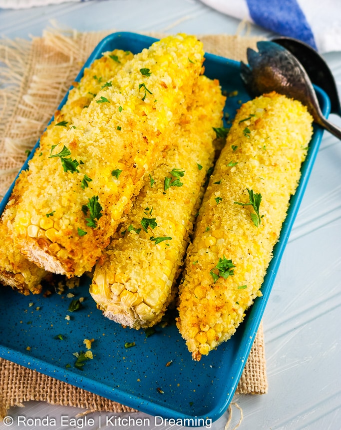 A plate of Air fryer corn on the cob with a set of serving tongs.