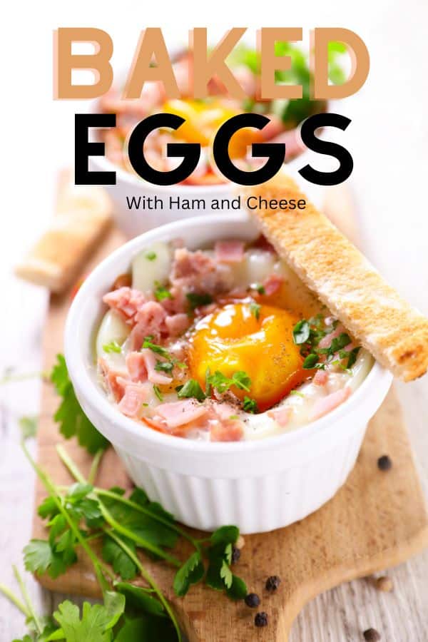 A pin image of two white ramekins containing baked eggs with ham and cheese. These are some freshly chopped herbs, whole parsley and toast sticks.