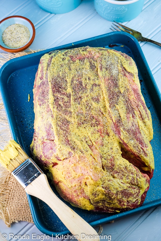 This is an in-process photo of a chuck roast covered in dijon mustard and coated in spice rub. It is ready to go into the smoker. 