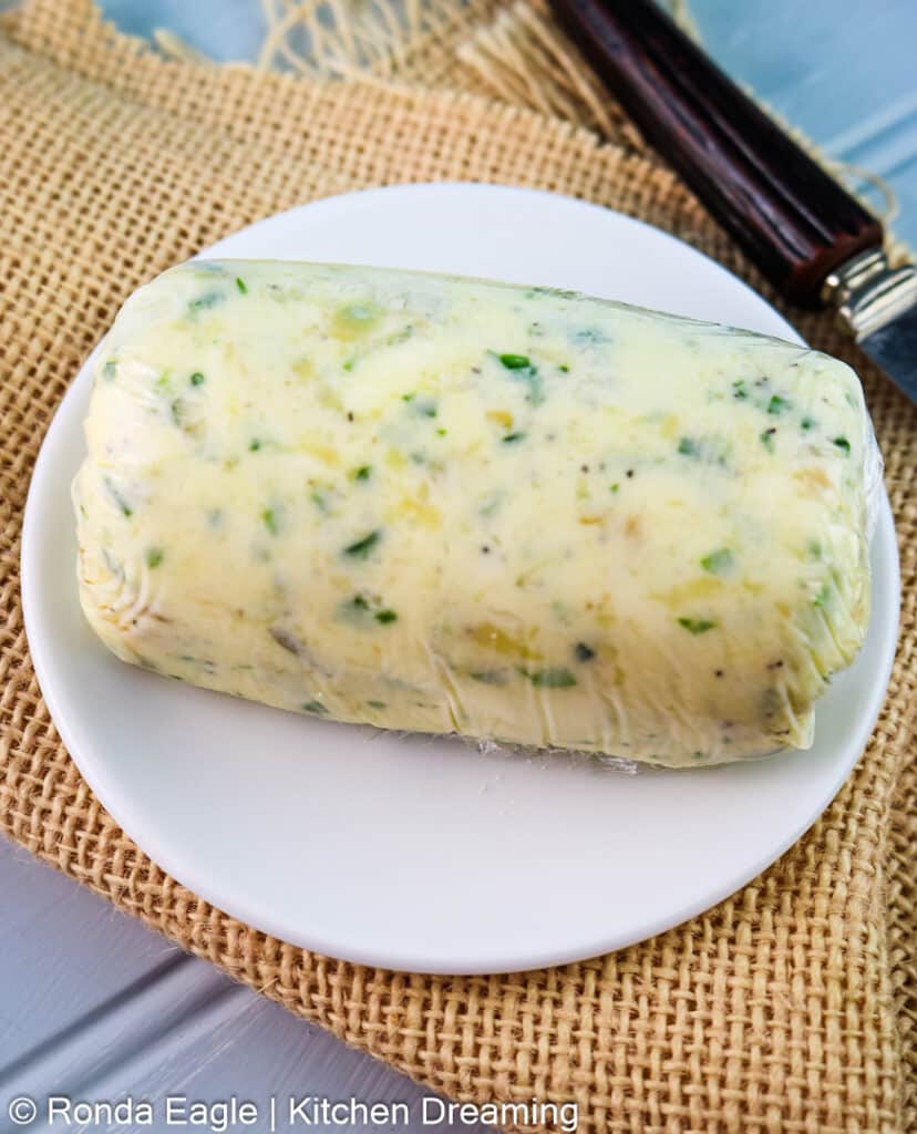 The compound butter after it has been transferred to plastic wrap and twisted into a log. It is now ready to chill so it can be cut into slices.