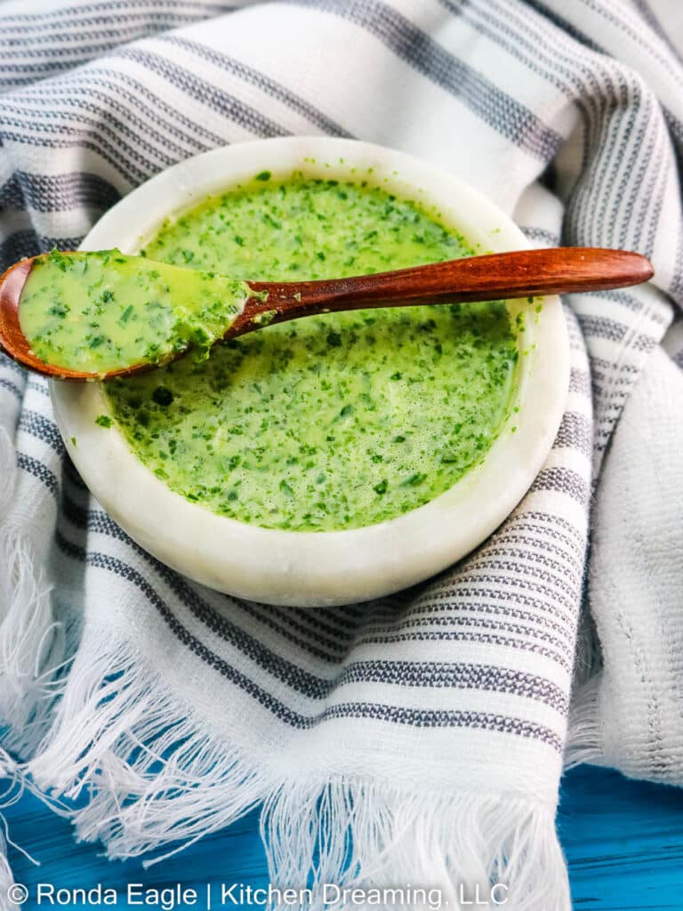 A small white dish is filled with a vibrant green mojo-chimichurri marinade.