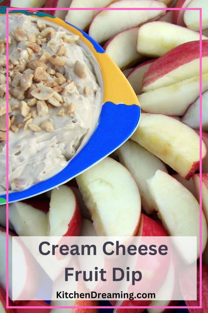 a pin image of a bowl of cream cheese fruit dip topped with crushed peanuts and surrounded by sliced apples.