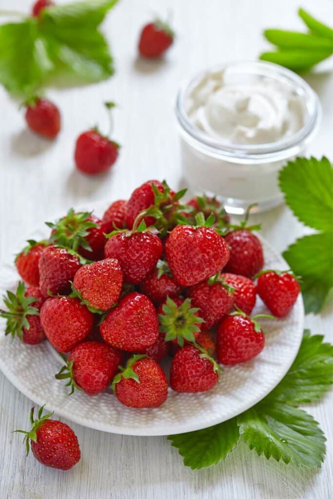 A small white plate filled with fresh strawberries.