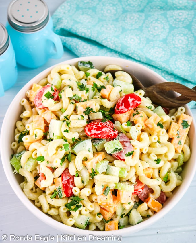Overhead image of a bowl of Garden pasta salad on a table with a blue mandala print napkin and salt and miniature blue mason jar salt and pepper shakers,