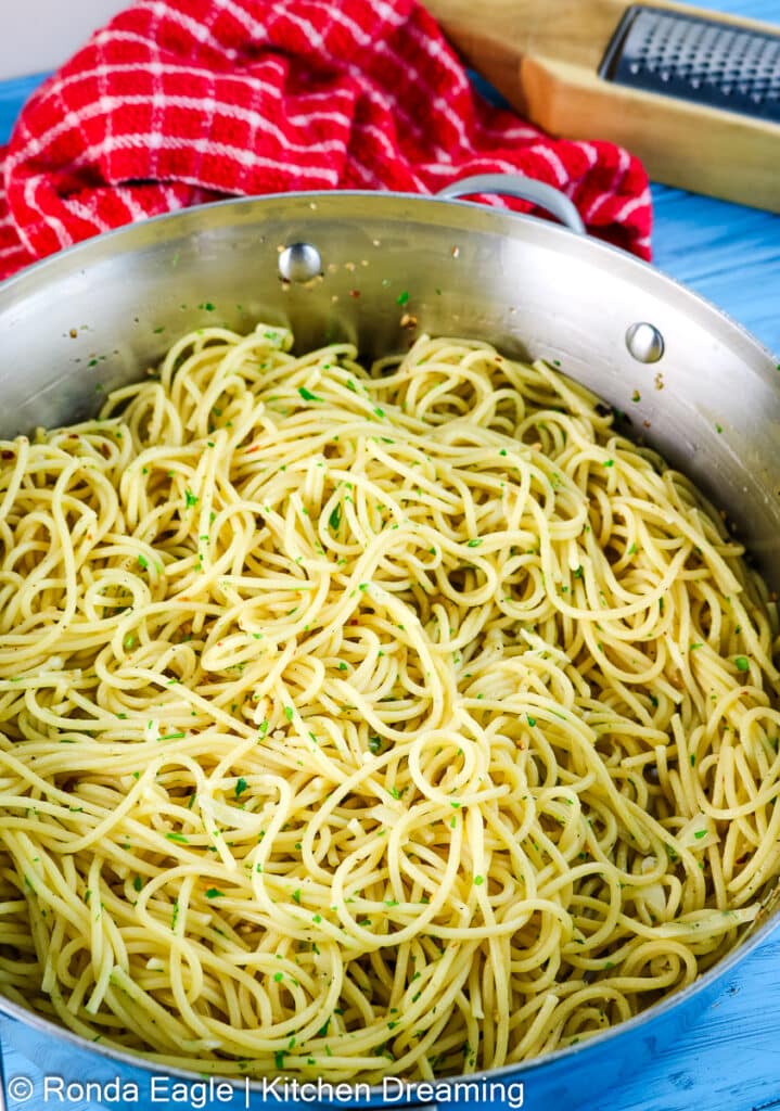 A deep pan filled with Aglio e olio which has just been tossed together in the pan.