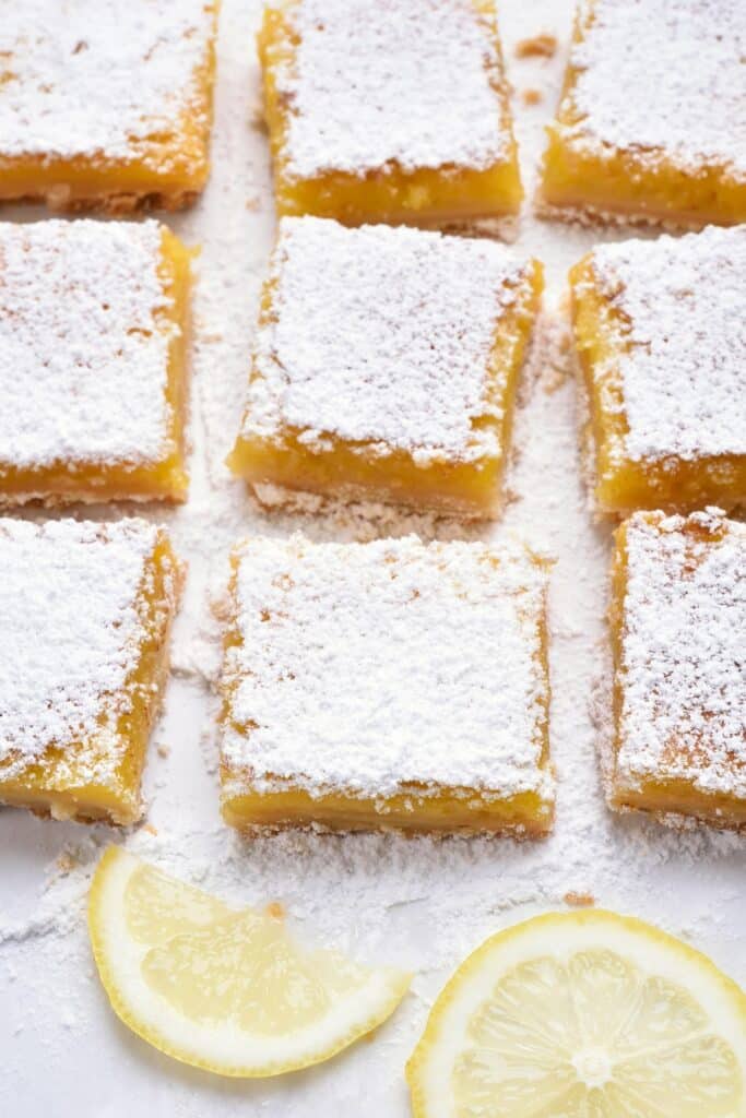 Lemon bars cut into individual squares dusted with powdered sugar.
