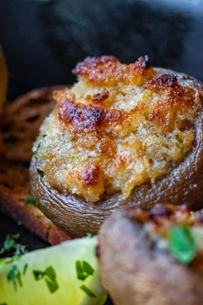 A close of of a baby Bella mushroom stuffed with chopped mushrooms stems, breadcrumbs, herbs, spices, and cheese. 