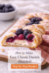 Close-up of easy cheese danish showing flaky crescent roll layers, cream cheese filling, and blackberries in a braided pastry.