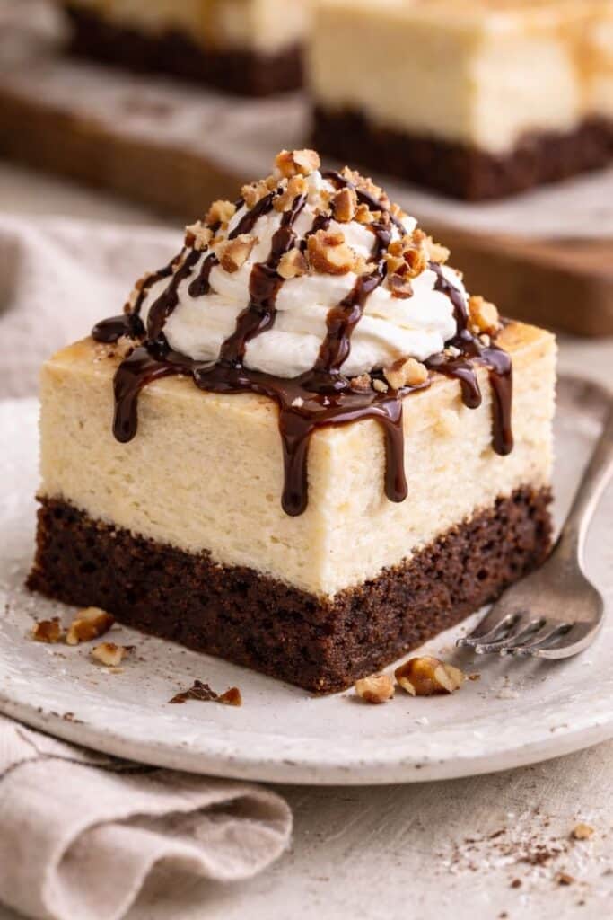 Decadent brownie cheesecake with swirls of rich cheesecake and fudgy brownie topped with chocolate chunks and a golden crust.