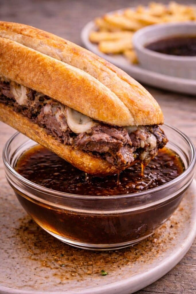 Easy Leftover Prime Rib French Dip Sandwich 3 Prime rib French dip sandwich being dipped into a bowl of rich au jus.