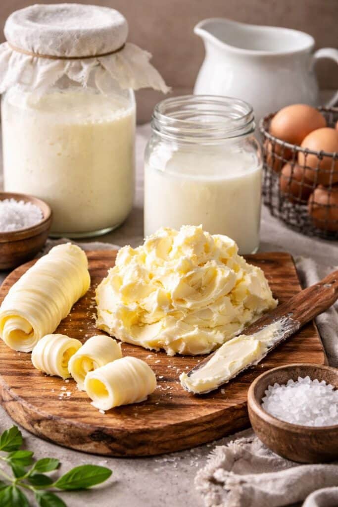 Homemade French butter on a wooden board with butter curls and sea salt in a rustic farmhouse kitchen.