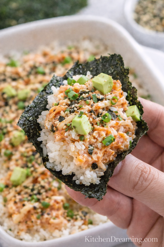 Salmon Sushi Bake Recipe (Easy, Creamy Sushi Bake) 5 A bite of salmon sushi bake recipe with rice, creamy salmon, furikake, green onions, and avocado on nori paper..