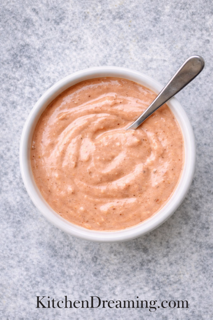 Copycat Zax Sauce Recipe (Easy Homemade Zaxby’s Dipping Sauce) 6 Zax sauce recipe close overhead texture shot in a white bowl with spoon.