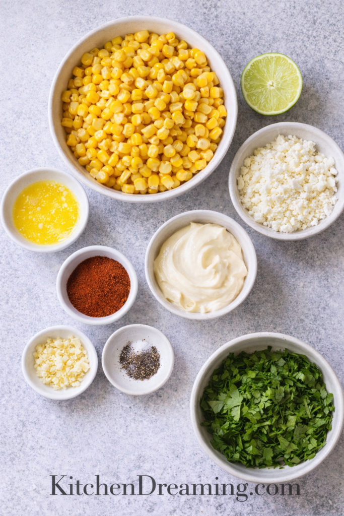 Authentic Esquites (Mexican Street Corn in a Cup) 2 Esquites ingredients arranged overhead with corn, cotija, lime, mayo, chili, and cilantro.