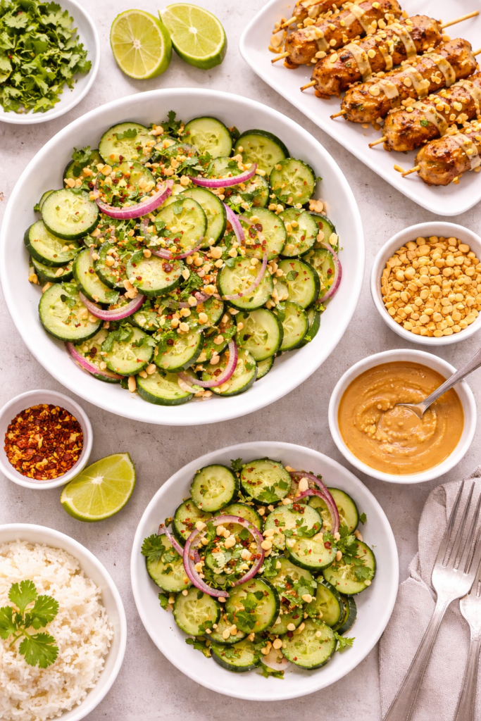 Thai Cucumber Salad Recipe (Easy, Sweet, Tangy & Refreshing) 4 Thai cucumber salad served overhead with grilled skewers, rice, lime, peanuts, and dipping sauce.